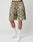 A person wears LIVE FAST DIE YOUNG Live Fast Nylon Shorts in green and beige camo with side pockets, white crew socks featuring LIVE FAST branding, and white sneakers, standing against a plain white background.
