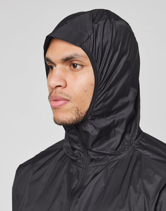 A person wears the LIVE FAST DIE YOUNG Live Fast Performance Running Jacket in black, regular fit with a visor hood up, looking left against a plain light gray background.