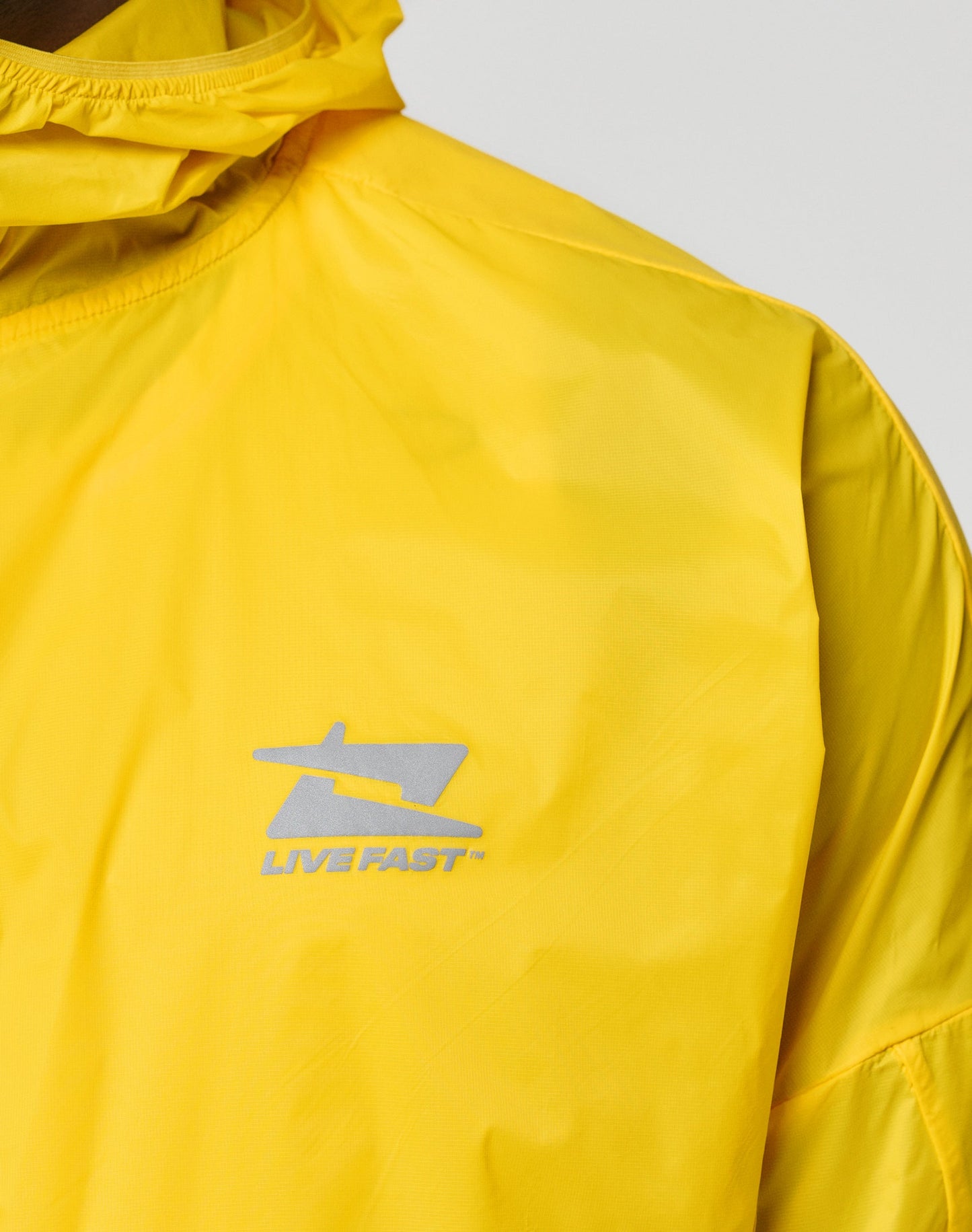 The LIVE FAST DIE YOUNG Live Fast Performance Running Jacket in bright yellow is shown from the back against a white background, featuring long sleeves, regular fit, and a very lightweight outer material for comfort.