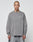 A person with a shaved head and neck tattoo models the LIVE FAST DIE YOUNG Basic Longsleeve—an oversize fit, 100% cotton gray shirt with a subtle chest logo—paired with gray pants against a plain white background.