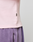 Close-up of a person wearing the Basic Waffle Longsleeve by LIVE FAST DIE YOUNG in light pink with ribbed cuffs and a black tag, paired with high-waisted purple sweatpants featuring oversize fit, visible pocket, and seam detail.