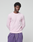 A young man with short curly hair wears the LIVE FAST DIE YOUNG Basic Waffle Longsleeve in light pink and purple drawstring cotton pants, standing against a plain light gray background with his hands behind his back.