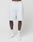 A person models LIVE FAST DIE YOUNG Basic Shorts in regular fit, light gray, knee-length with elastic waistband, paired with white crew socks and sneakers. Only the lower body is shown against a plain white background.