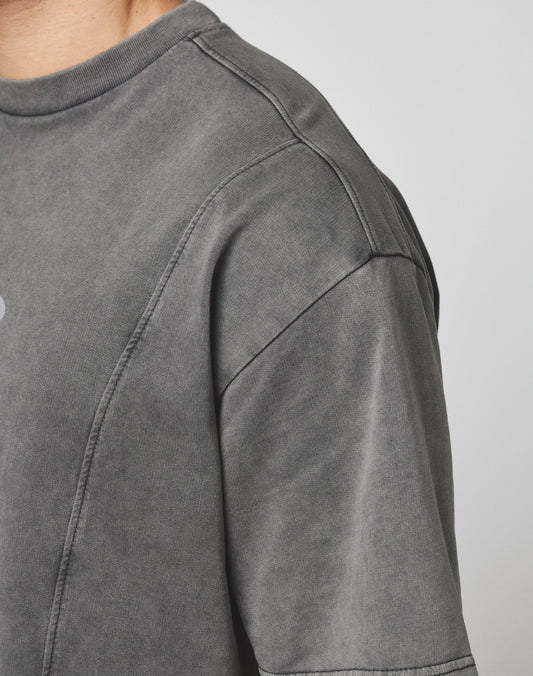 Close-up of a person wearing the LIVE FAST DIE YOUNG Live Fast Wave Tee in faded grey, highlighting the shoulder, sleeve, and part of the neck against a plain light background.