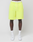 A person wearing LIVE FAST DIE YOUNG Basic Shorts in bright yellow with a logo print and elastic waistband, plus white socks and sneakers, stands against a plain white background. The shorts’ waistband displays the LIVE FAST text. Only the lower half is shown.