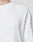 Close-up of a person wearing the LIVE FAST DIE YOUNG Basic Script Waffle Longsleeve, a textured white crew-neck shirt with an oversize fit and subtle logo embroidery near the chest. The background is plain and light-colored.