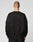 A person with a shaved head is shown from behind, wearing the LIVE FAST DIE YOUNG LFDY Wavy Sweater in black with subtle curved stitching and black pants, standing against a plain light background.