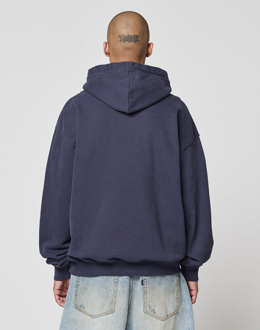 A person with a shaved head and a neck tattoo is seen from behind in a LIVE FAST DIE YOUNG Live Fast Plain Hooded hoodie and light blue jeans, standing against a plain background.