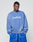A man wears the Basic LiveFast Sweater by LIVE FAST DIE YOUNG in faded blue with LiveFast in white, paired with matching blue shorts, standing hands-in-pockets against a plain background.