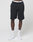 A person stands against a plain background, wearing LIVE FAST DIE YOUNG Basic Shorts with an elastic waistband and visible branding, paired with white athletic shoes and socks. The image is cropped from waist to feet.