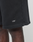 Close-up of a person wearing LIVE FAST DIE YOUNG Basic Shorts in black, featuring a regular fit and white LFDY™ logo embroidered near the hem. Only part of the shorts and the person’s upper leg are visible.