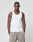 A man with a neutral expression stands against a plain background wearing the LIVE FAST DIE YOUNG Blank Rib Tank in white and beige pants, with his hands in his pockets.