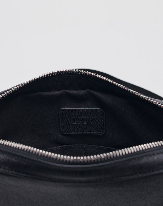 Close-up of the inside of a black LIVE FAST DIE YOUNG Airliner Bag with a silver zipper, showing a black label stitched inside and featuring embossed LFDL logo letters.