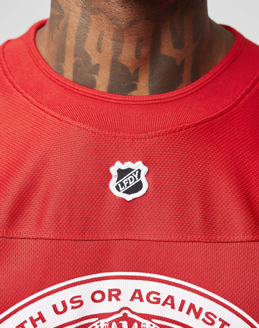 A close-up of a person in a red LFDY Hockey Jersey by LIVE FAST DIE YOUNG, featuring an oversize fit, black chest badge, bold neck tattoos, and an eye-catching Ärmelprint.
