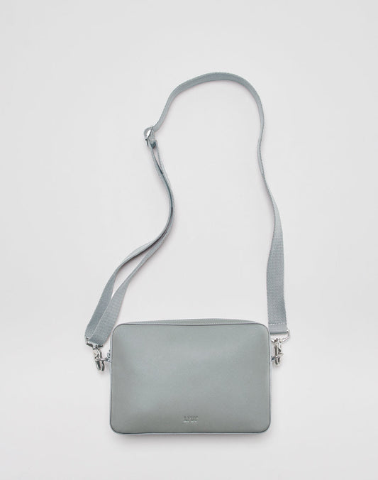 The LIVE FAST DIE YOUNG Airliner Bag is a light gray, rectangular crossbody with an embossed logo, matching adjustable strap, and silver hardware. Shown in one size against a plain white background.