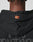 Close-up of the back of a person wearing the LIVE FAST DIE YOUNG Print Over Hooded in Oversize Fit, featuring a small orange and red logo on the hood, subtle gray text below, and made from 100% Baumwolle.