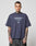 A person with short hair and visible tattoos wears an oversize fit, dark navy LFDY Triple Racing Tee by LIVE FAST DIE YOUNG with a Multilogo Frontprint reading LIVE FAST CF 40, standing against a plain light gray background.