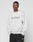 A man wears the light gray Basic LiveFast Sweater by LIVE FAST DIE YOUNG, featuring LiveFast™ on the front, paired with black athletic shorts, standing against a plain white background with his hands in his pockets.
