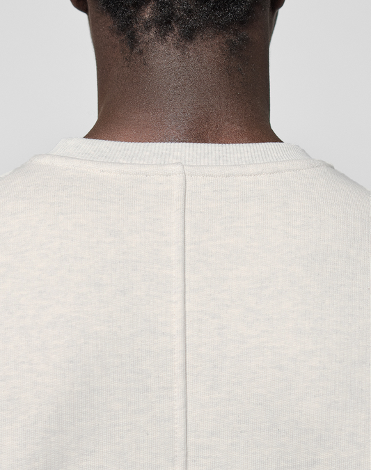 Close-up of the back of a person's neck and shoulders, wearing the LIVE FAST DIE YOUNG LFDY Heavyweight Lounge Sweater. This light-colored, textured oversize crewneck features a central seam and is crafted from 100% Baumwolle for comfort and durability.