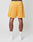 A person stands with their back to the camera, wearing LIVE FAST DIE YOUNG LFDY Oval Mesh Shorts in bright yellow, featuring a regular fit, elastic waistband, and back pocket, paired with white crew socks and sneakers against a plain background.