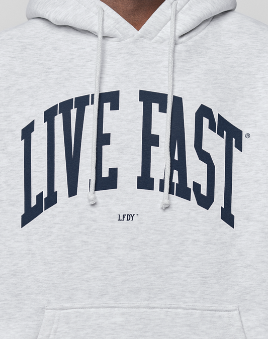 A close-up of the LIVE FAST DIE YOUNG Live Fast College Hooded, an oversized light gray hoodie in soft cotton, with bold navy "LIVE FAST" front print, smaller "LFDY" underneath, and visible drawstrings.