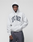 A person wears the LIVE FAST DIE YOUNG Live Fast College Hooded, an oversized light gray cotton hoodie with a "LIVE FAST" front print, standing against a plain gray background with hands in pockets and a neutral expression.