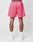 A person is shown from the back wearing LIVE FAST DIE YOUNG LFDY Oval Mesh Shorts in bright pink with a regular fit, elastic waistband, and back pocket, paired with white socks and sneakers. The background is plain white.