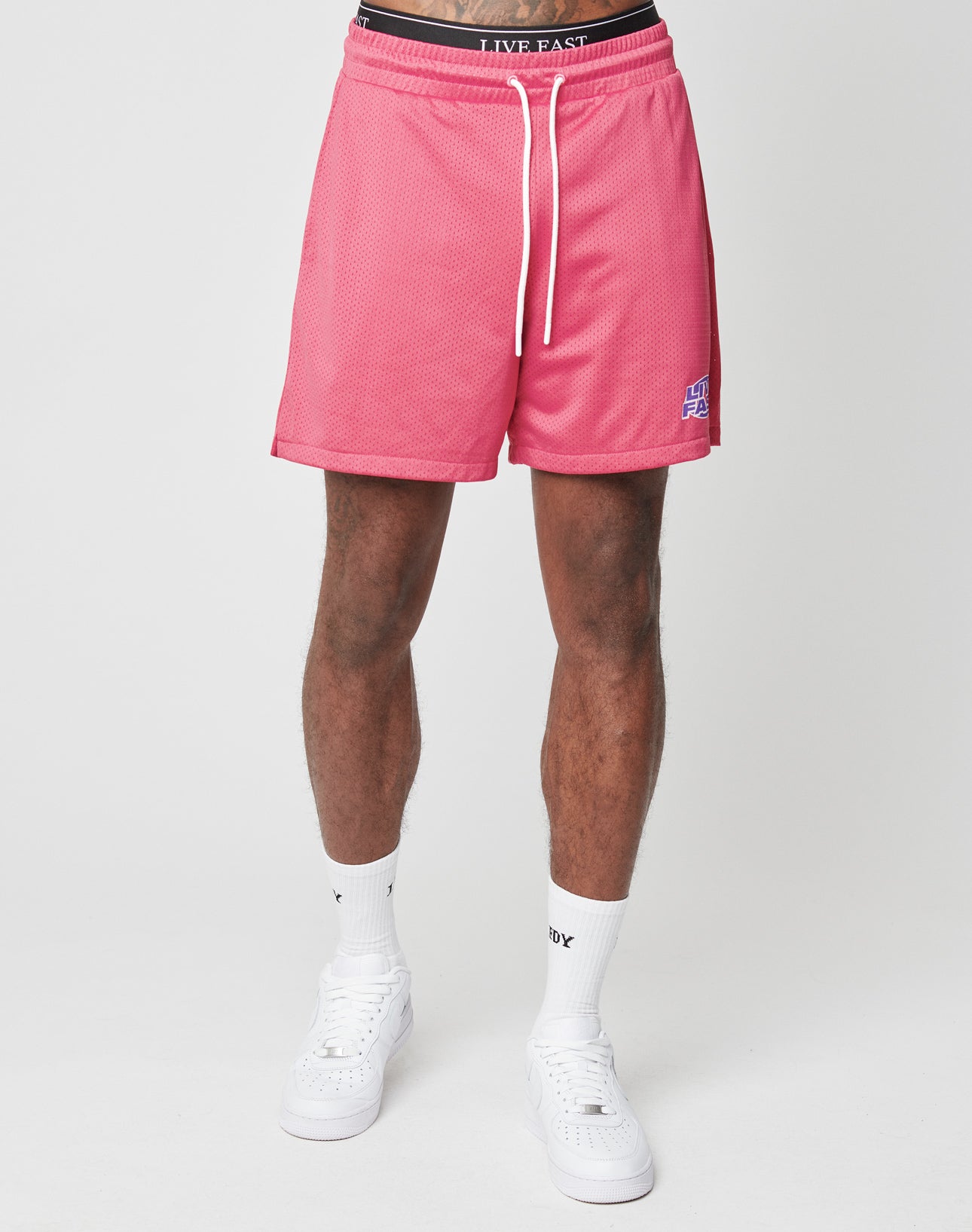 A person models the LFDY Oval Mesh Shorts by LIVE FAST DIE YOUNG, featuring an elastic waistband, paired with white socks and sneakers. Only the lower half of their body is shown against a plain white background.