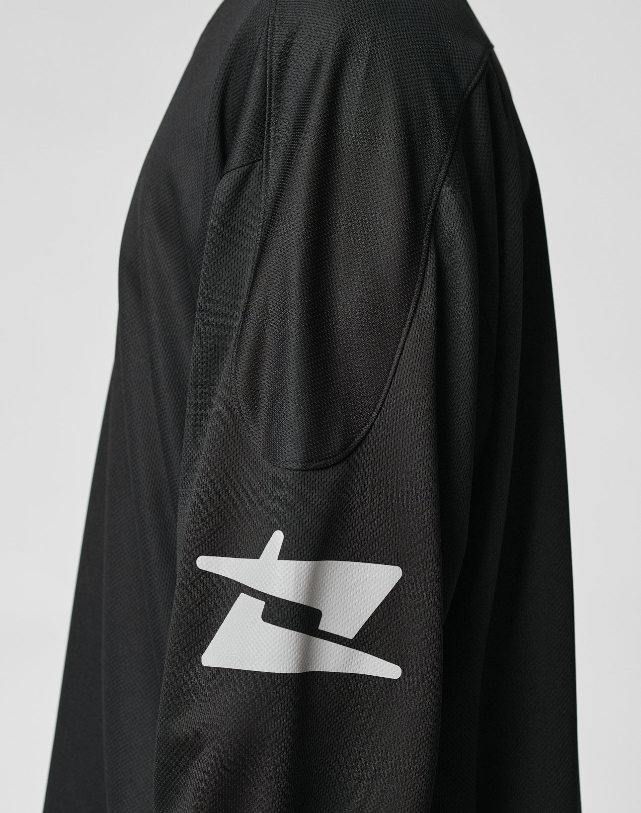 A close-up of the LIVE FAST DIE YOUNG Live Fast Jersey, a black oversized long-sleeve shirt. The focus is on the shoulder and sleeve, which features a bold white reflective print near the elbow against a plain light background.