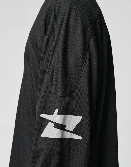 A close-up of the LIVE FAST DIE YOUNG Live Fast Jersey, a black oversized long-sleeve shirt. The focus is on the shoulder and sleeve, which features a bold white reflective print near the elbow against a plain light background.