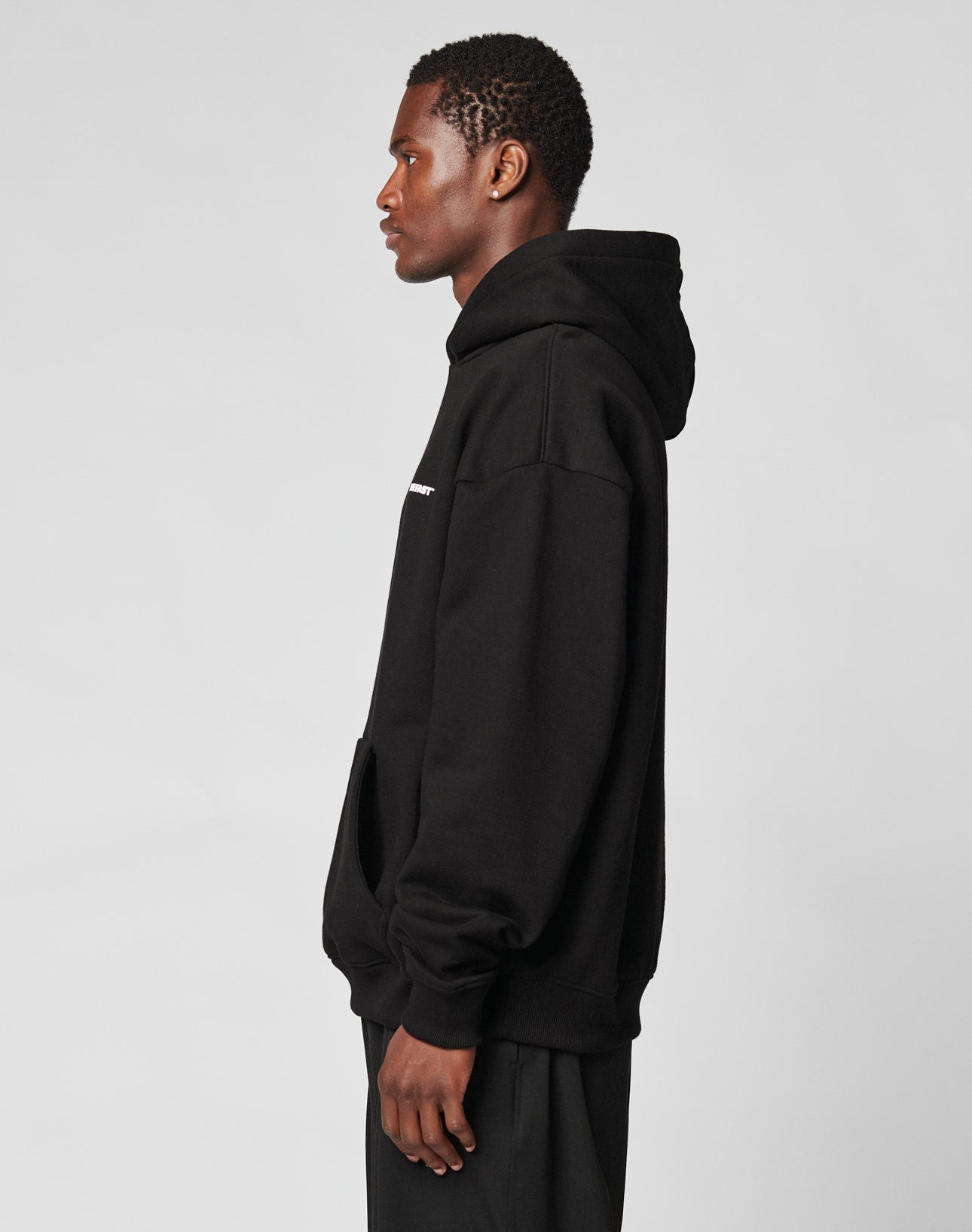 A man stands in profile against a plain background, wearing the Live Fast Plain Hooded sweatshirt by LIVE FAST DIE YOUNG, featuring an oversize fit and soft Baumwolle, with his hands by his sides.