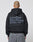 A person with a shaved head and a tattoo on the back of their scalp wears the LIVE FAST DIE YOUNG Basic 510 Hooded Zip in Oversize Fit with a large gray Backprint text, paired with gray jeans.