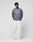 A person with short curly hair stands against a plain light background, wearing LIVE FAST DIE YOUNG Worker Pants in white 100% Baumwolle with a Carpenter Pocket and a gray T-shirt with white text, paired with white sneakers.
