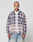 A person stands facing forward against a plain light gray background, wearing the LIVE FAST DIE YOUNG Vintage Flannel—a blue, white, and red plaid shirt with Vintage Waschung and Zweiteiliger Hemdkragen—over a white t-shirt and light blue jeans.