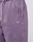 Close-up of a person wearing the LIVE FAST DIE YOUNG Basic Wide Jogger in purple, featuring a white drawstring and embroidered LFDY logo near the pocket.