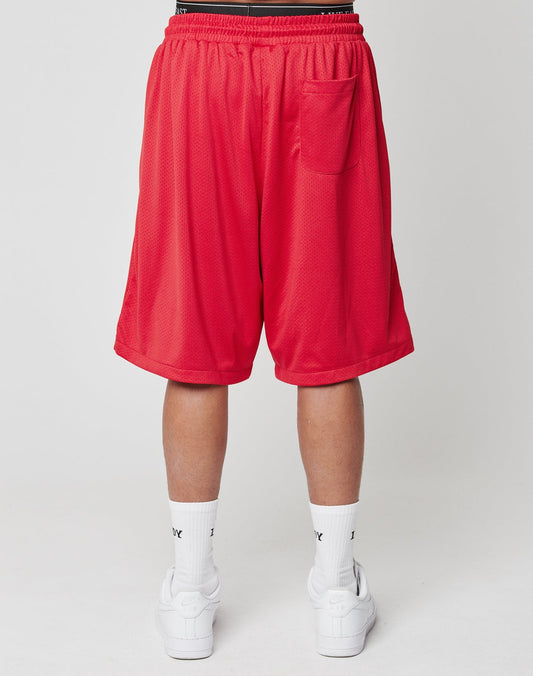 A person stands against a plain background, wearing LIVE FAST DIE YOUNG’s Live Fast IV Ever Shorts with side pockets, elastic waistband, back pocket, plus white Nike socks and sneakers. The image focuses on the lower body from behind.