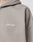 A close-up shows part of a shoulder and hood wearing the taupe Basic Script Hooded Zip by LIVE FAST DIE YOUNG, featuring Vintage-Waschung and a white cursive Live Fast logo embroidered on the chest.