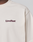 A close-up of a cream-colored Basic 210 Tee by LIVE FAST DIE YOUNG, featuring "LiveFast" in dark purple on the left chest. Only the upper torso, neck, and shoulder are visible. Made from 100% Baumwolle.