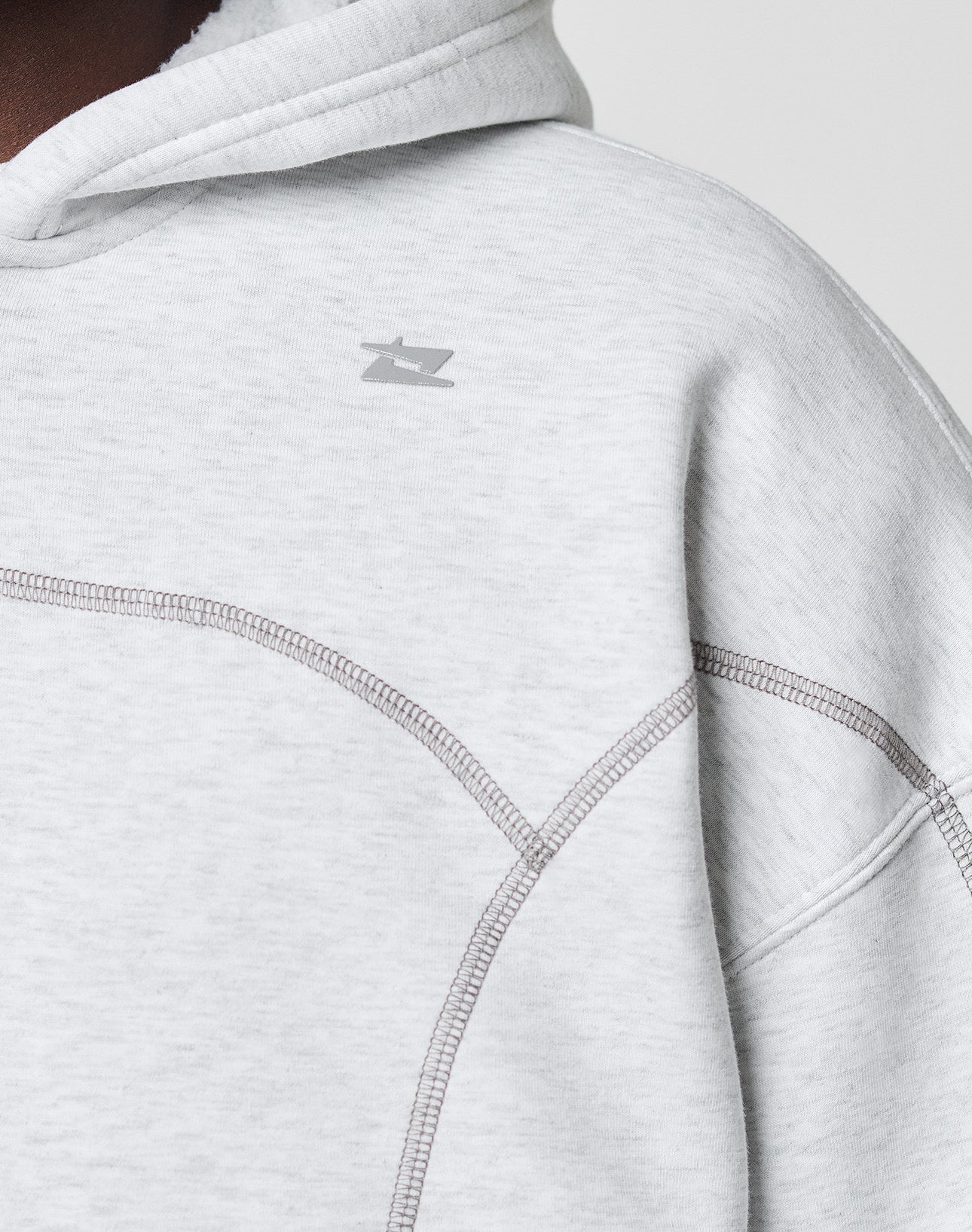 A close-up of the LIVE FAST DIE YOUNG LFDY Active Fleece Hooded Zip in light gray, featuring an oversize fit, visible stitching, and a small minimalist chest logo, worn by a person.