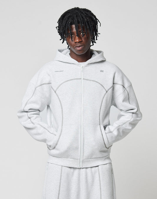 A person with short dreadlocks wears the LIVE FAST DIE YOUNG LFDY Active Fleece Hooded Zip in light gray and matching pants, posing against a plain background with hands in the sweatshirt’s pockets.