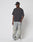 A person in a black cap, LIVE FAST DIE YOUNG LFDY Monaco Boys Tee in dark gray Oversize Fit, baggy light-wash jeans in Vintage Optik, and white sneakers stands against a plain white background with hands in pockets, looking to the side.