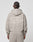 A person with short, braided hair is seen from behind, wearing the LIVE FAST DIE YOUNG Basic 510 Hooded Zip in light taupe, featuring white LiveFast™ HvySweat 510g/m² and small text printed on the back.
