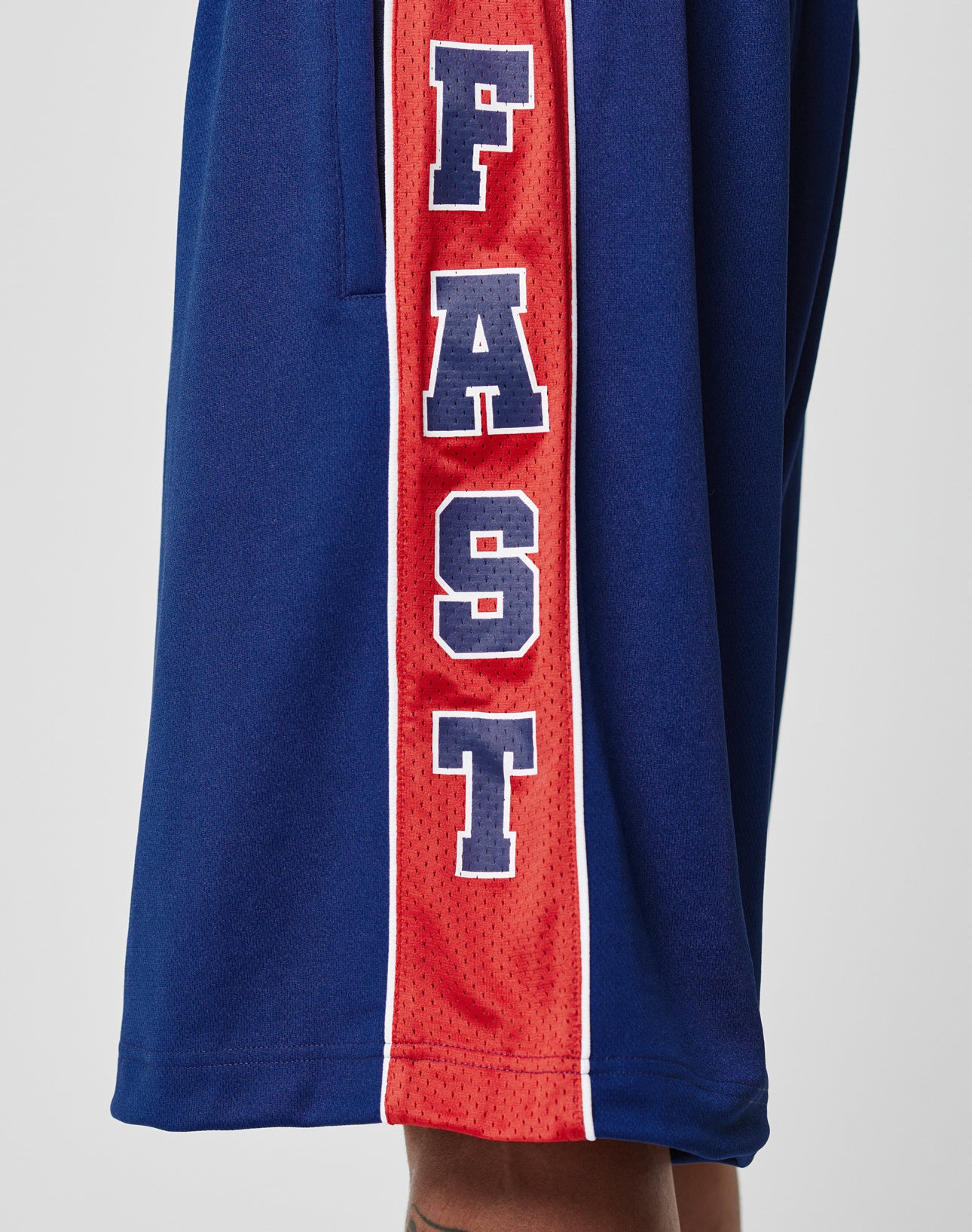 A close-up of Striped Mesh Shorts by LIVE FAST DIE YOUNG in blue with a red side stripe, elastic waistband for comfort, and FAST printed in large white letters outlined in navy along the stripe.