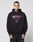 A man with short dark hair and hand tattoos wears the LIVE FAST DIE YOUNG LFDY Triple Racing Hooded, an oversized black cotton hoodie with pink LIVE FAST, multilogos, and a 40 graphic, paired with black pants. He stands against a plain light background.