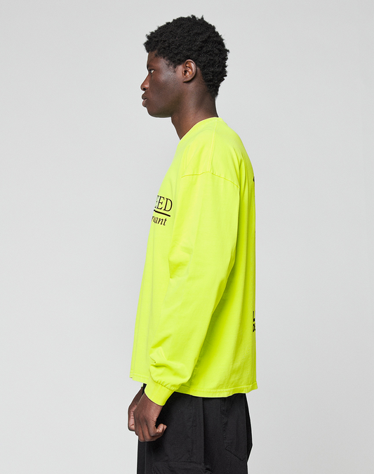 A person stands in profile against a plain background, wearing the LIVE FAST DIE YOUNG LFDY Real Est.8 Longsleeve in neon yellow with black front and back print, paired with black pants. Made of 100% Baumwolle.