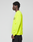A person stands in profile against a plain background, wearing the LIVE FAST DIE YOUNG LFDY Real Est.8 Longsleeve in neon yellow with black front and back print, paired with black pants. Made of 100% Baumwolle.