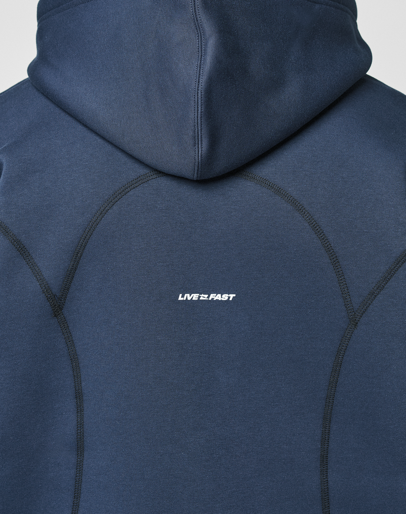 A close-up of the back of the navy LFDY Active Fleece Hooded Zip by LIVE FAST DIE YOUNG, featuring prominent stitching and a small white LIVE FAST logo print at the center.