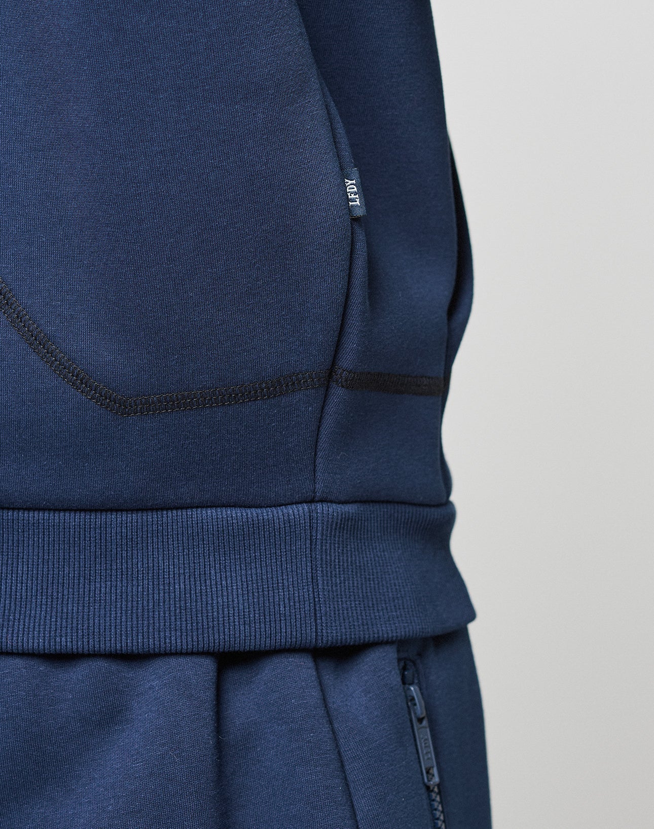 Close-up of a person wearing the LIVE FAST DIE YOUNG LFDY Active Fleece Hooded Zip in navy blue, featuring an oversize fit, visible stitching, zipper details, and a subtle logo print on the side.