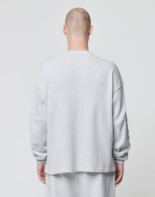 A person with a shaved head stands facing away from the camera in a light gray LIVE FAST DIE YOUNG Basic Script Waffle Longsleeve and matching pants, both featuring subtle logo-stitch details, against a plain light gray background.