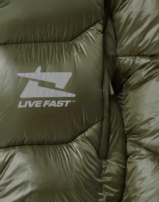 Close-up of the Live Fast Puffer Jacket by LIVE FAST DIE YOUNG in olive green shiny nylon, with a white “LIVE FAST” logo, reflective graphic print, oversize fit, and prominent quilted texture.